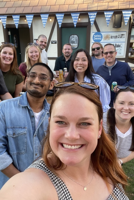 Group of coworkers smiling together outdoors at an Oktoberfest-themed team event